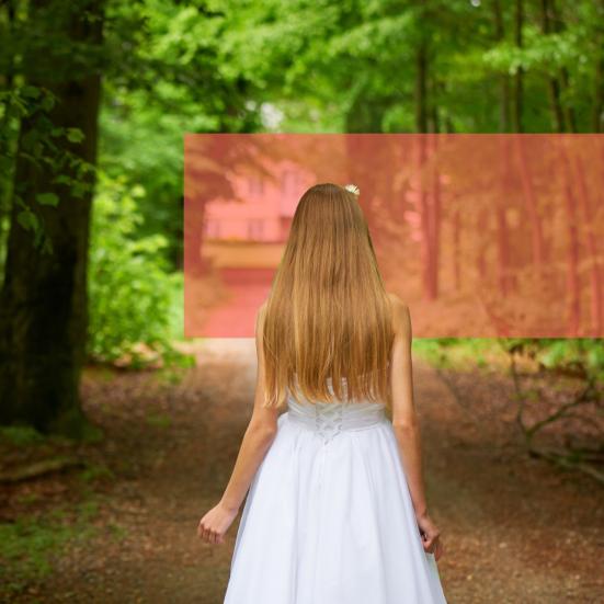 Konfirmand i hvid kjole på vej i bøgeskov