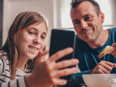 Pige kigger på mobiltelefon og far kigger med
