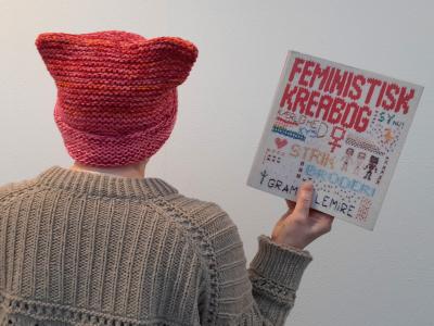 Person set bagfra med strikhue og trøje og kreabog i hånden